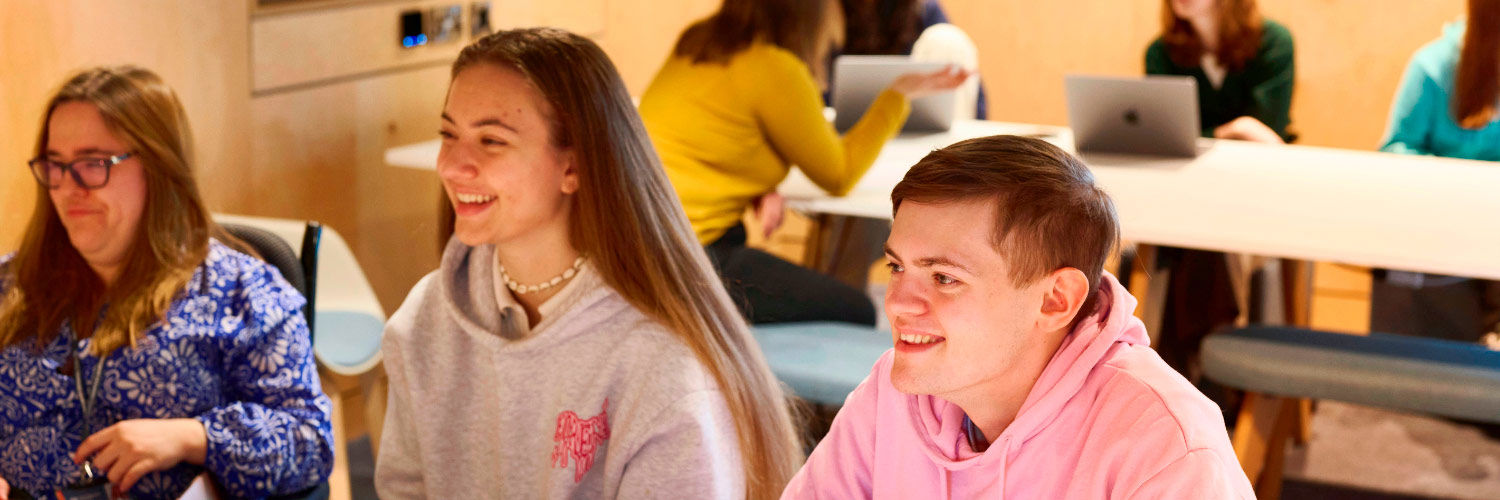 Students smiling while working in the library