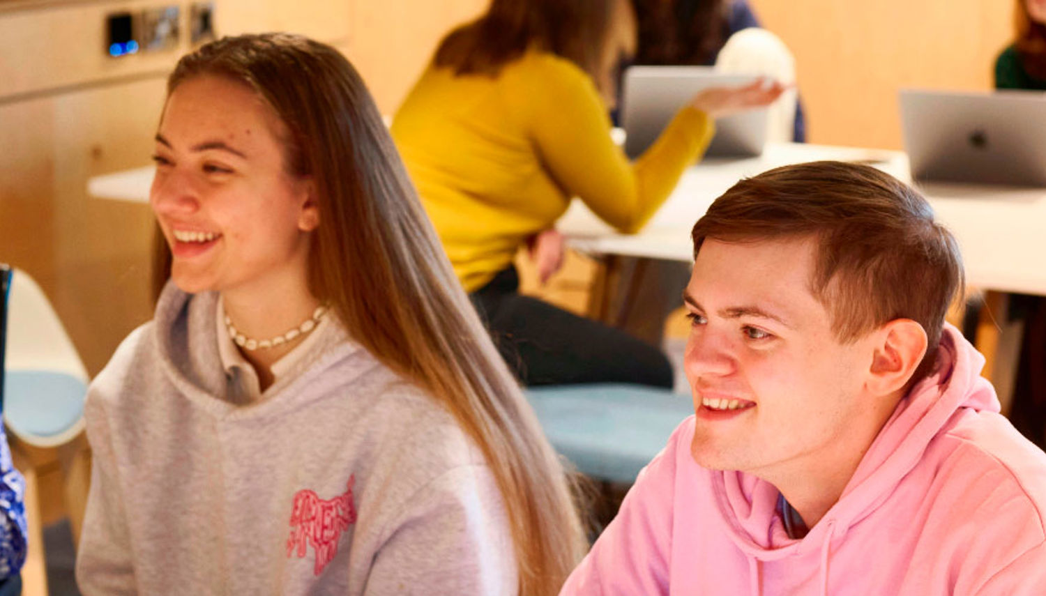 Students smiling while working in the library