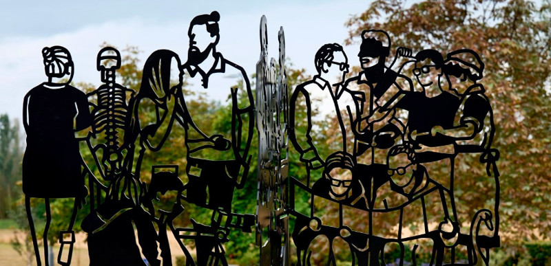 A steel sculpture of linocut-style cutouts of different individuals.