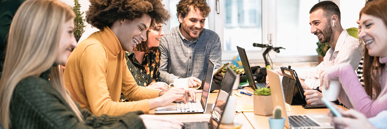Group of colleagues sitting around a table chatting with laptops