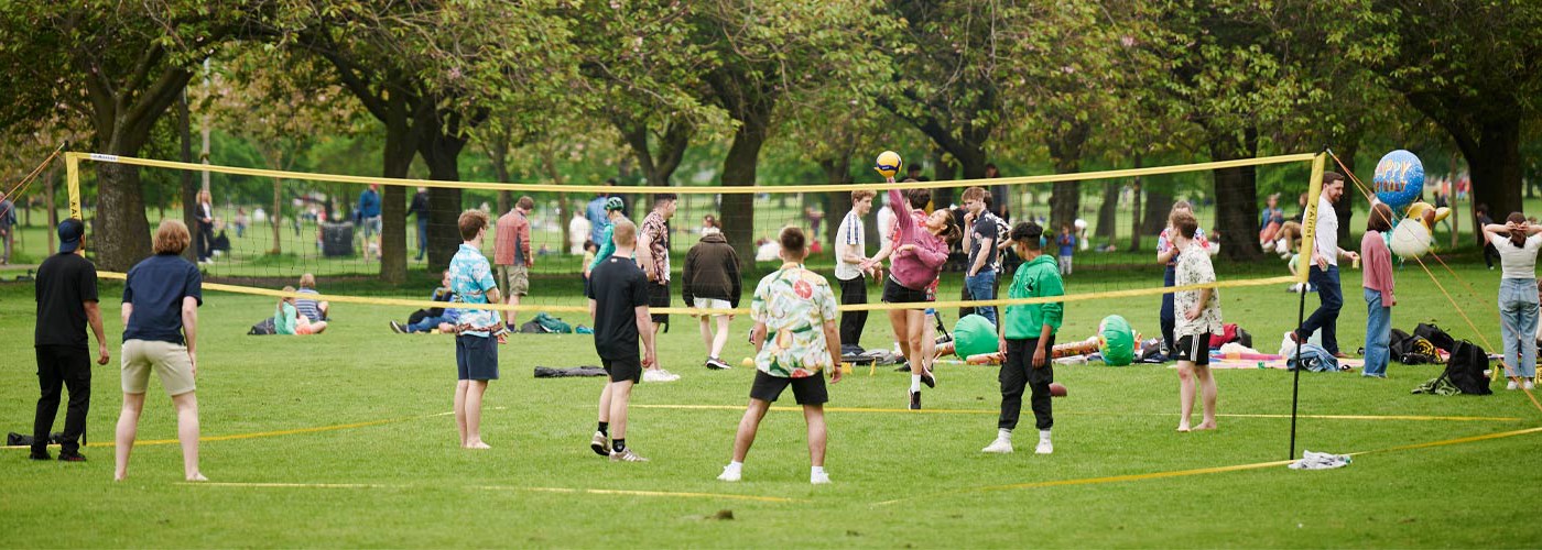 A group of people playing volleyball in a park