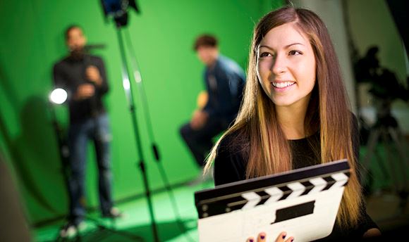 Female in front of a green screen with cameras