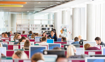 A view of the QMU library with students seated amongst various rows of computer desks.