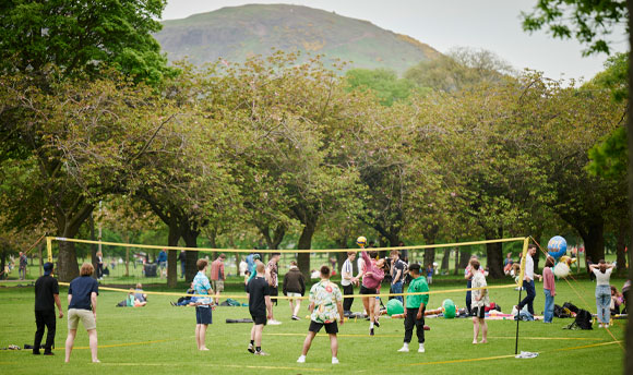 A group of people playing volleyball in a park