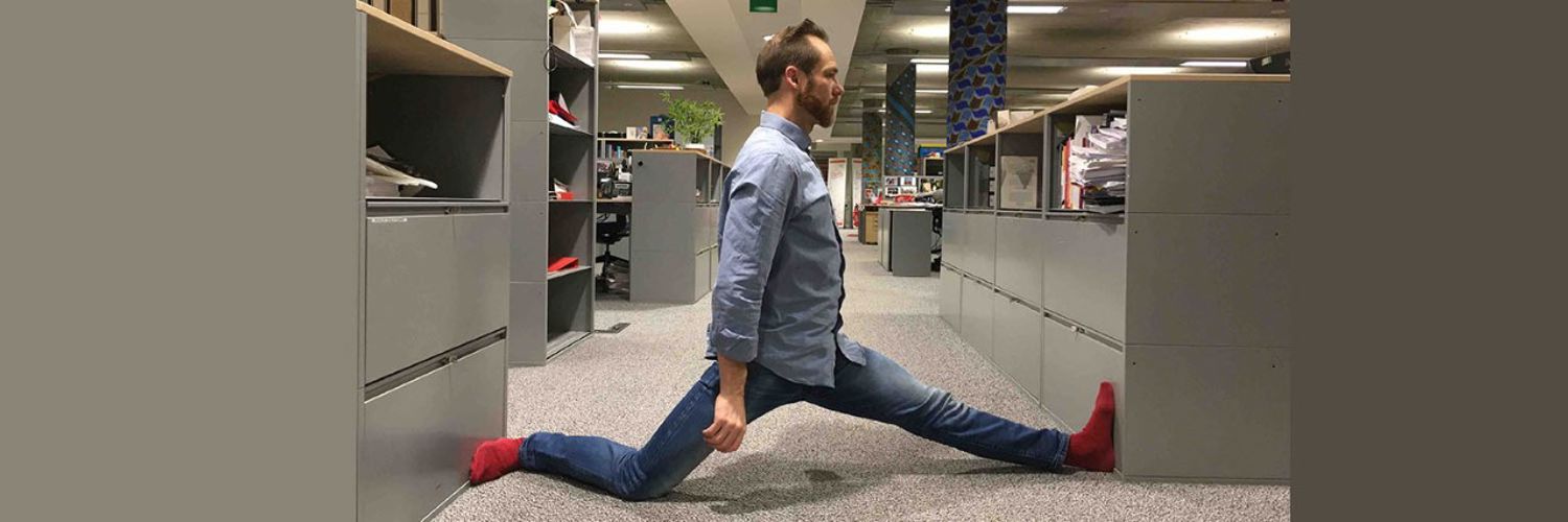 Anthony fitting himself in the space between two desks
