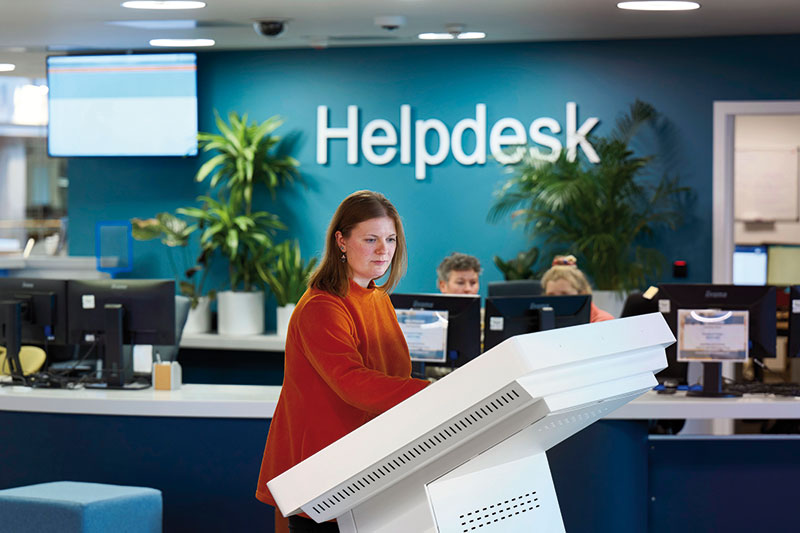 Female Student using a self service screen in front of the Helpdesk