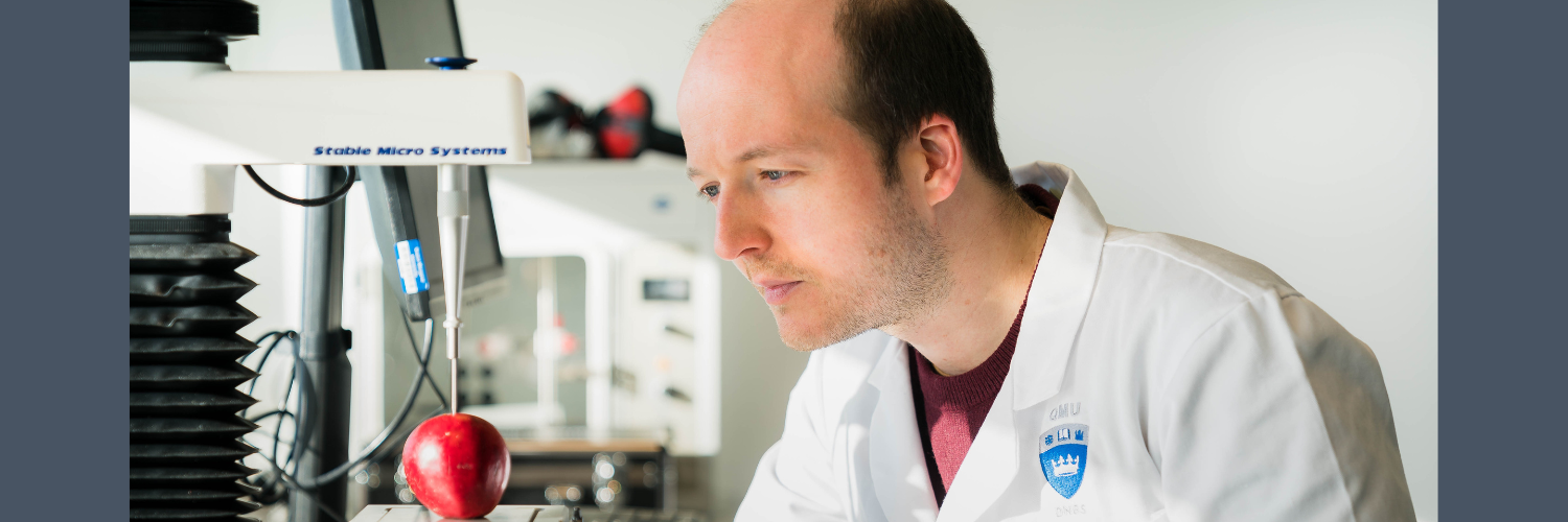 QMU researcher in a food lab examining at an apple