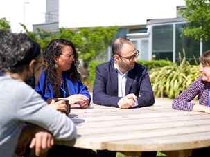 Image of staff conversing outside QMU in the sunshine