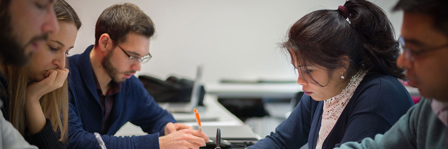 A group of students working closely together on a group project, taking notes by hand.