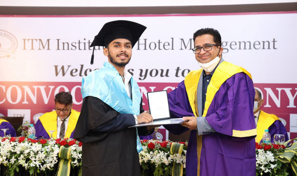 QMU/ITM graduate Atharva Gurav receives his degree certificate.