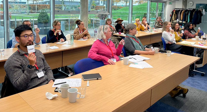 A group of people showing 'higher' or 'lower' answer cards for a practical game