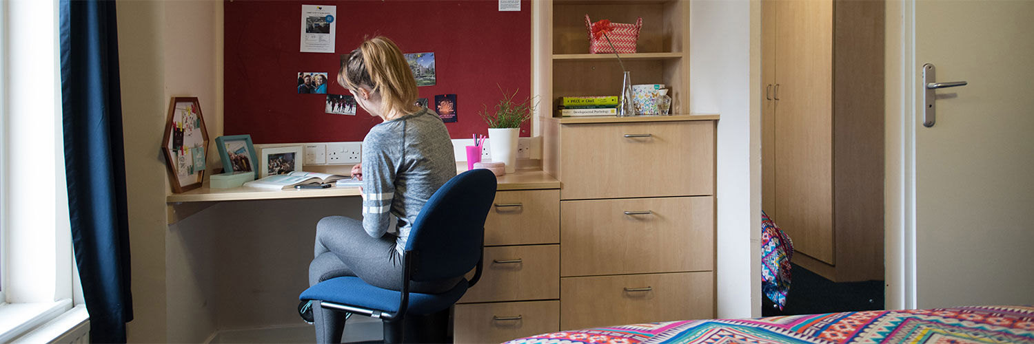 A QMU student at a desk in her student accommodation