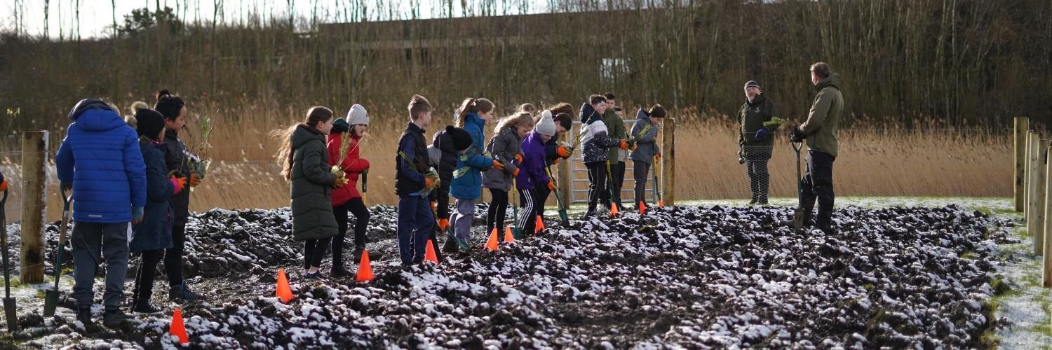 Group of school children planting trees in the Wee Forest at QMU's campus