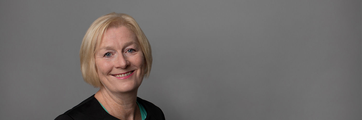 A woman with short blonde hair smiles towards the camera