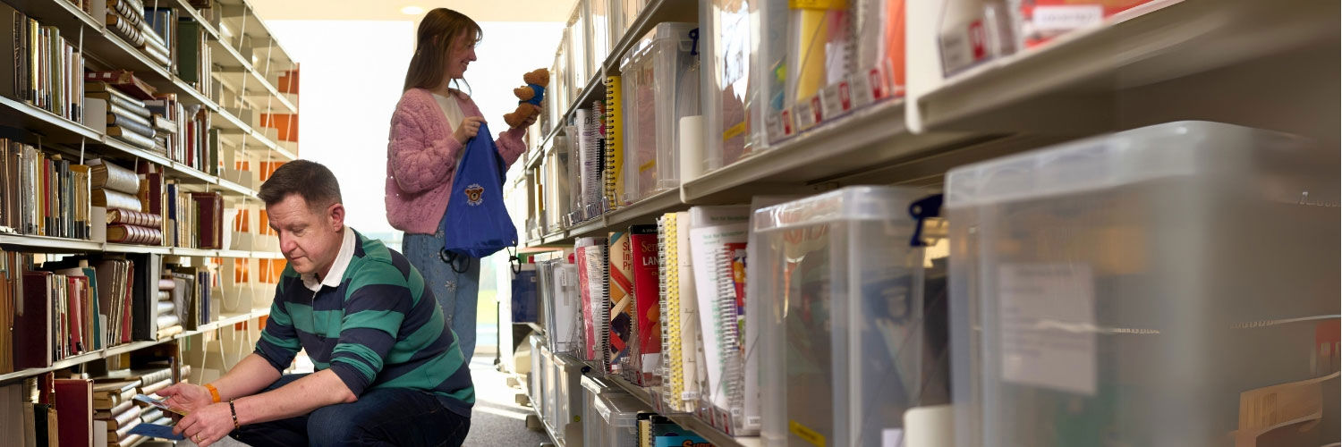 Two students browse a range of resources within the QMU library