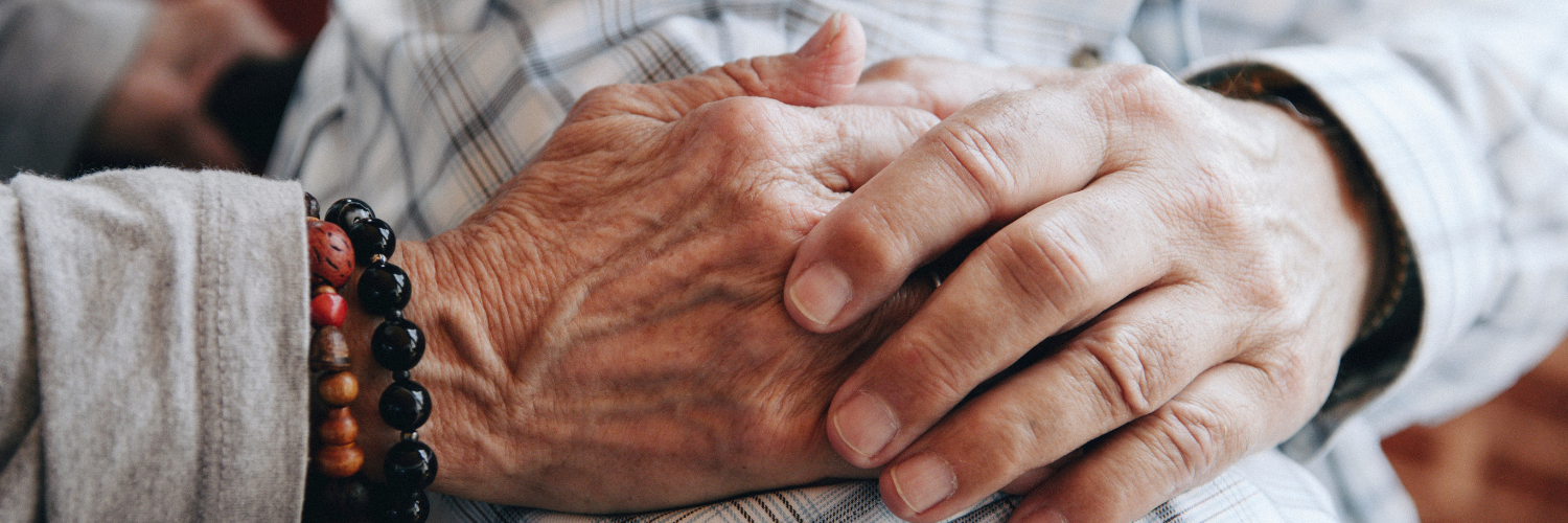two pairs of older people's hands touching