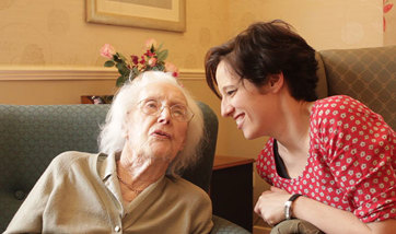 A young woman chatting with an elderly woman in a care home