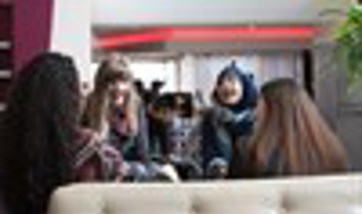 A group of students sit talking and laughing on sofas, Queen Margaret University, Edinburgh