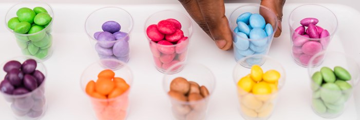 Person making a selection from clear cups holding colourful food samples.