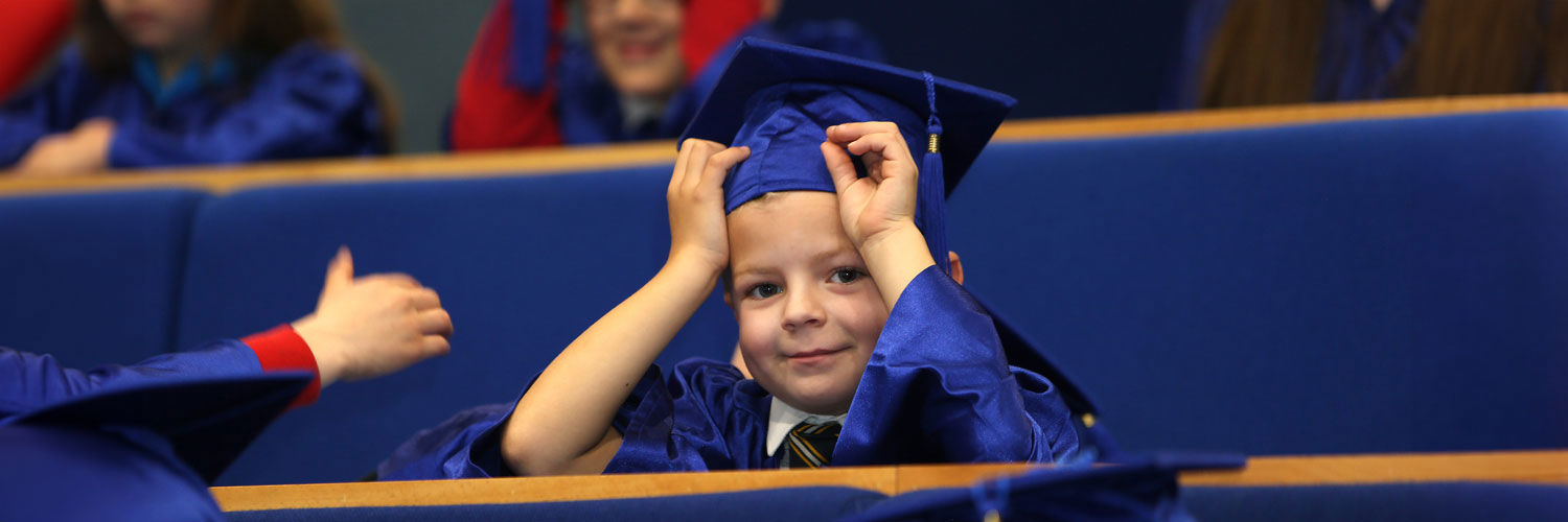 A young boy wearing a royal blue cap and gown at the Children's University graduation ceremony.