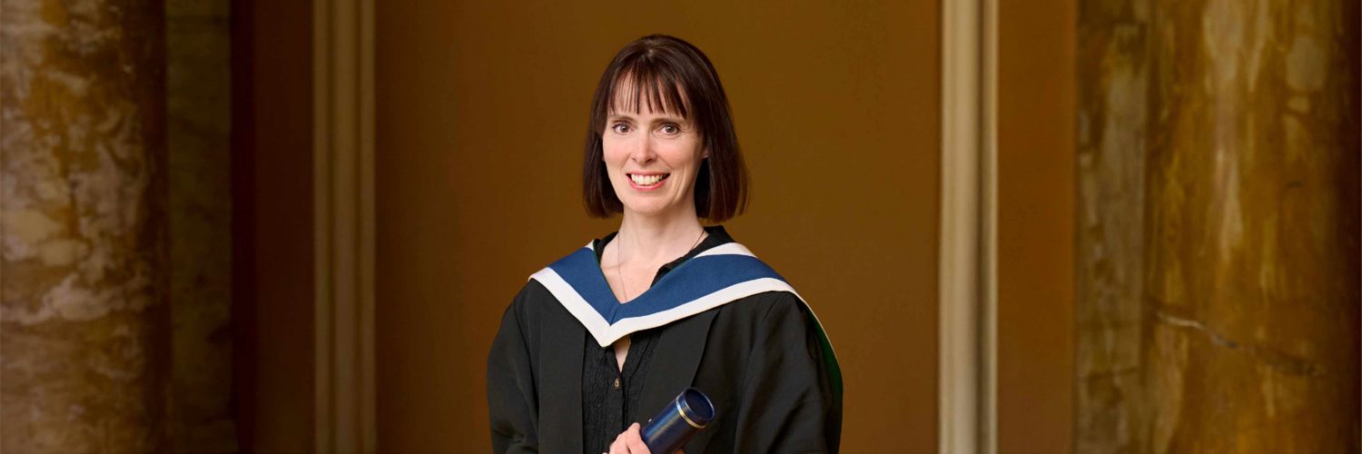 portrait shot of female with bobbed hair smiling and wearing her graduation robe