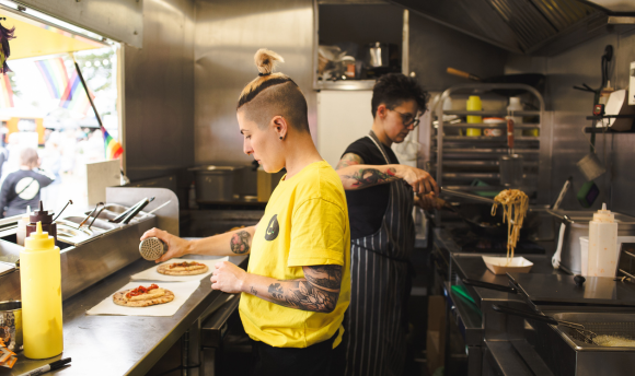 Two people in a food truck cooking. 