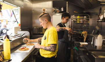 Two people in a food truck cooking. 